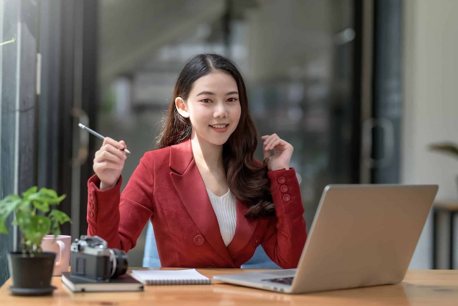beautiful young asian businesswoman sitting looking at camera with laptop in office